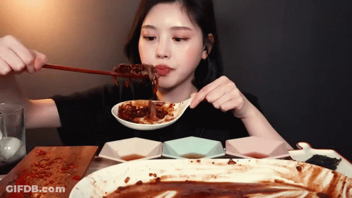 A Woman Is Eating A Large Plate Of Food With A Spoon GIF