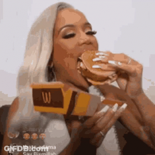 A Woman Is Eating A Mcdonald 'S Hamburger While Holding A Box Of Mcdonald 'S . GIF