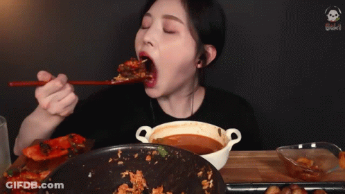 A Woman Is Eating A Meal With Chopsticks And A Bowl Of Soup GIF