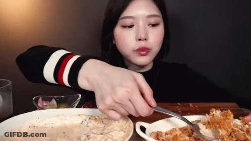 A Woman Is Eating A Plate Of Food With A Fork GIF