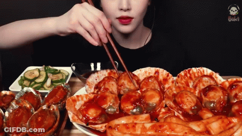 A Woman Is Eating A Plate Of Food With Chopsticks . GIF