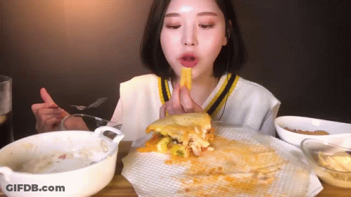 A Woman Is Eating A Sandwich With A Fork And Knife . GIF