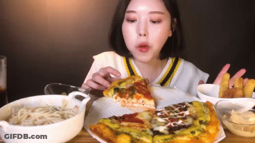 A Woman Is Eating A Slice Of Pizza And French Fries . GIF