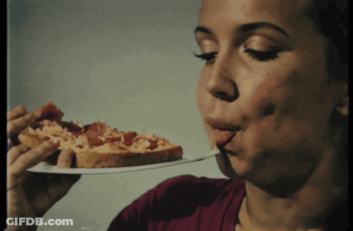 A Woman Is Eating A Slice Of Pizza With Her Tongue Out GIF