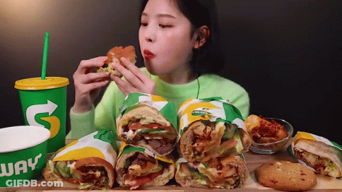 A Woman Is Eating A Subway Sandwich And Drinking A Subway Cup GIF