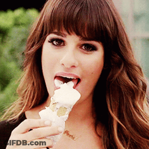 A Woman Is Eating An Ice Cream Cone While Wearing A Necklace With The Word Peace On It GIF