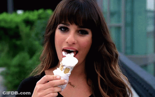 A Woman Is Eating An Ice Cream Cone With A Necklace That Says ' Nicole ' On It GIF