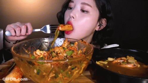 A Woman Is Eating Food With A Fork From A Bowl GIF
