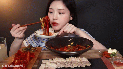 A Woman Is Eating Food With Chopsticks And A Bowl Of Food GIF