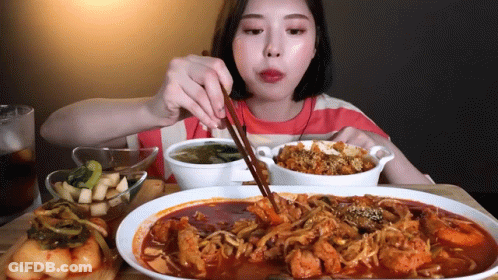 A Woman Is Eating Food With Chopsticks And A Bowl Of Soup GIF