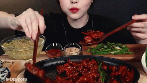 A Woman Is Eating Food With Chopsticks And A Spoon GIF