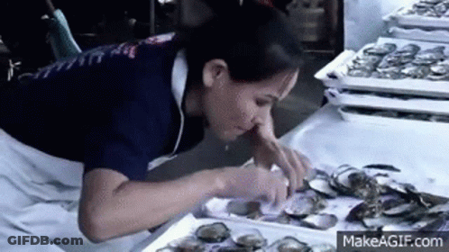 A Woman Is Eating Oysters At A Market . GIF