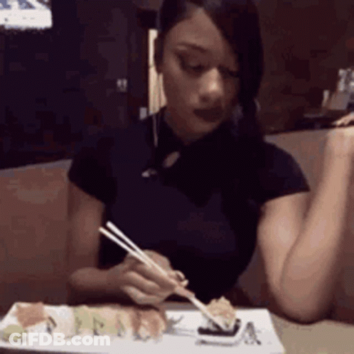 A Woman Is Eating Sushi With Chopsticks . GIF