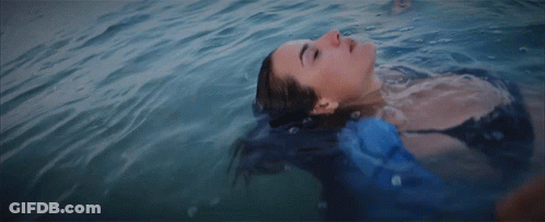 A Woman Is Floating On Her Back In The Water GIF