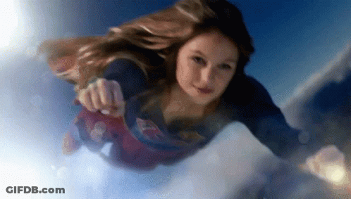A Woman Is Flying Through The Air Wearing A Superman Costume . GIF
