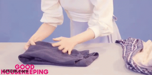 A Woman Is Folding Clothes And The Words Good Housekeeping Are Above Her GIF