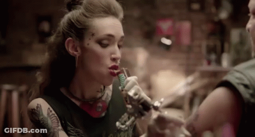 A Woman Is Getting A Tattoo On Her Arm In A Tattoo Parlor . GIF