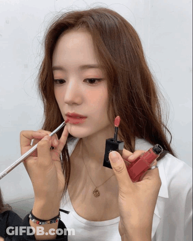 A Woman Is Getting Her Lips Painted With A Red Lipstick GIF