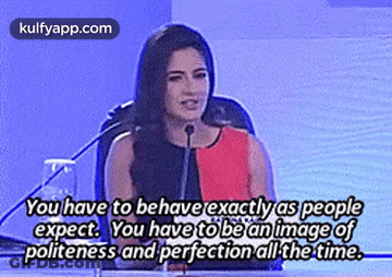 A Woman Is Giving A Speech In Front Of A Microphone With A Quote About Politeness And Perfection All The Time . GIF