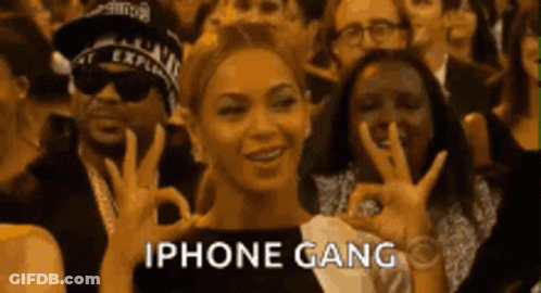 A Woman Is Giving An Ok Sign In Front Of A Crowd Of People With The Words Iphone Gang Written Below Her GIF