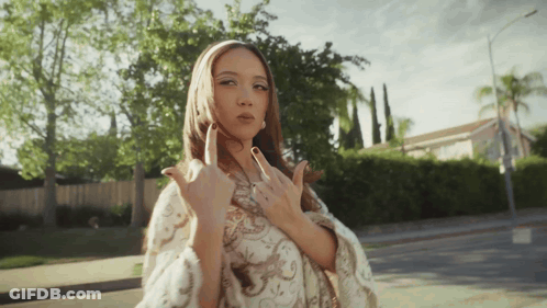 A Woman Is Giving The Middle Finger While Standing On The Sidewalk GIF