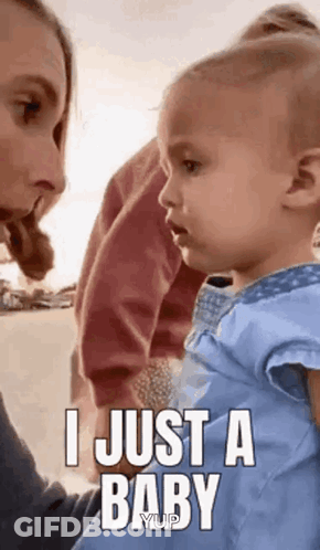 A Woman Is Holding A Baby And The Baby Is Looking At The Camera . GIF