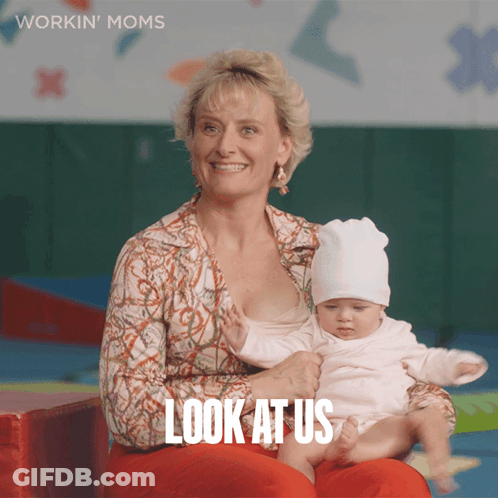 A Woman Is Holding A Baby And The Words Look At Us Are On The Bottom GIF