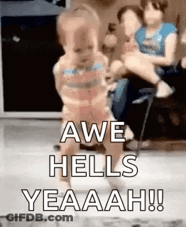 A Woman Is Holding A Baby In Her Arms And A Baby Is Walking On A Floor . GIF