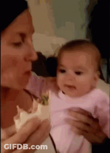 A Woman Is Holding A Baby In Her Arms And Looking At It . GIF