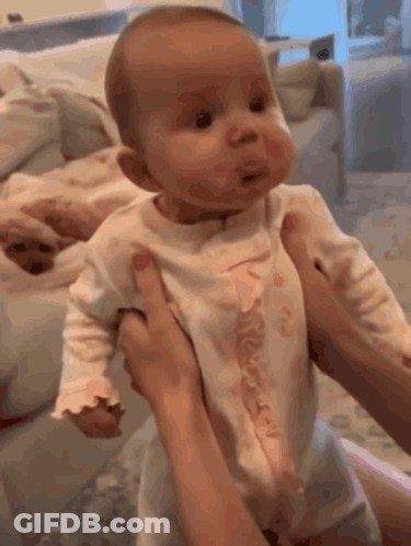 A Woman Is Holding A Baby In Her Arms And Making A Face GIF