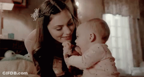 A Woman Is Holding A Baby In Her Arms In A Bedroom . GIF