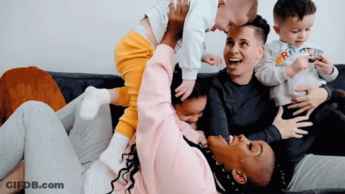 A Woman Is Holding A Baby In Her Arms While Another Woman Holds A Baby In Her Lap GIF