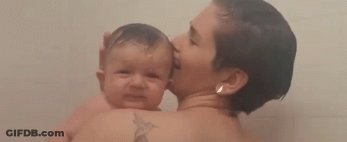 A Woman Is Holding A Baby In Her Arms While Taking A Bath . GIF