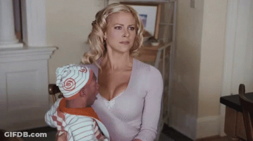 A Woman Is Holding A Baby Wearing A Hat With A Swirl On It GIF