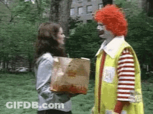 A Woman Is Holding A Bag Of Mcdonald 'S French Fries And Talking To A Clown . GIF