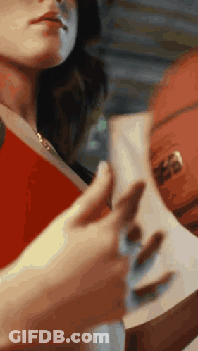 A Woman Is Holding A Book And A Basketball GIF