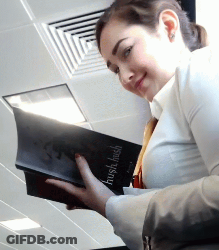 A Woman Is Holding A Book That Says Hush Hush On It GIF