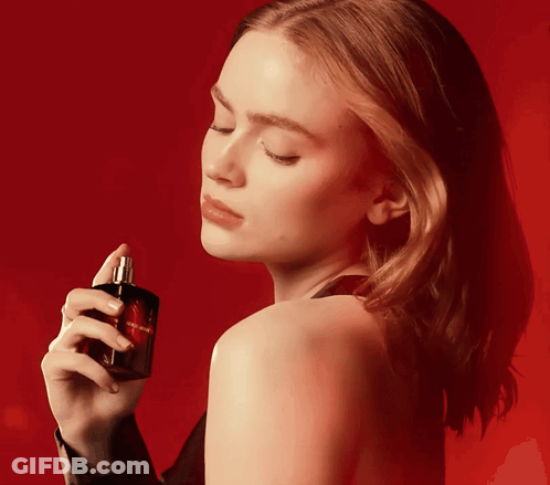A Woman Is Holding A Bottle Of Perfume That Says Yves Saint Laurent On It GIF