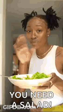 A Woman Is Holding A Bowl Of Salad And Eating It With A Fork . GIF