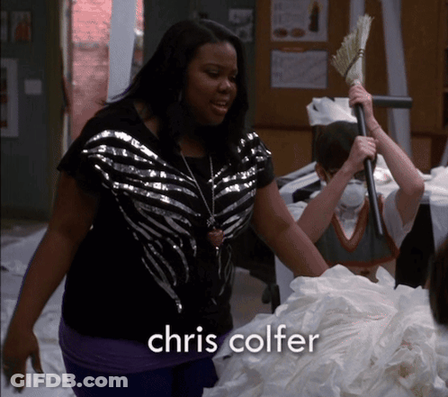 A Woman Is Holding A Broom And The Name Chris Colfer Is On The Bottom GIF