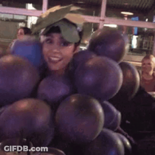 A Woman Is Holding A Bunch Of Balloons And Smiling . GIF