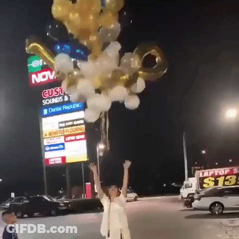A Woman Is Holding A Bunch Of Balloons In Front Of A Building That Says Gusto Sounds GIF