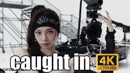 A Woman Is Holding A Camera With The Words Caught In 4K Ultra Hd GIF