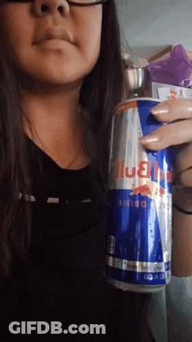A Woman Is Holding A Can Of Red Bull Energy Drink GIF