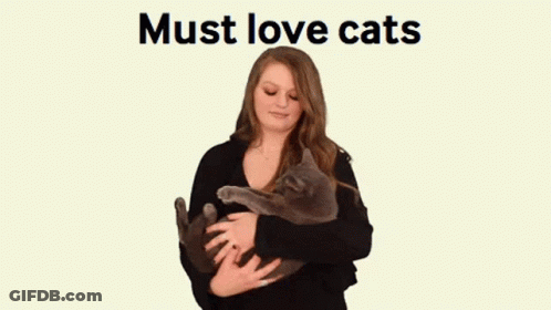 A Woman Is Holding A Cat In Her Arms With The Words Must Love Cats Behind Her GIF