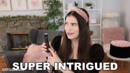 A Woman Is Holding A Cell Phone And The Words Super Intrigued Are On The Screen GIF