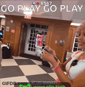 A Woman Is Holding A Cell Phone In Front Of A Sign That Says Exit GIF