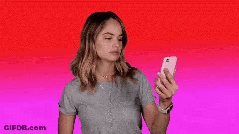 A Woman Is Holding A Cell Phone In Her Hand And The Word Blocked Is Visible . GIF
