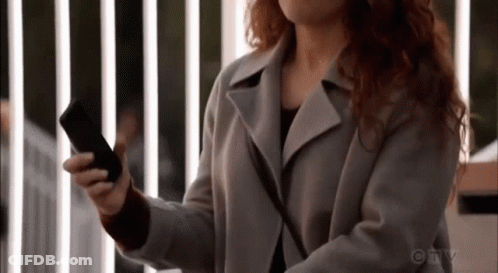 A Woman Is Holding A Cell Phone In Her Hand . GIF