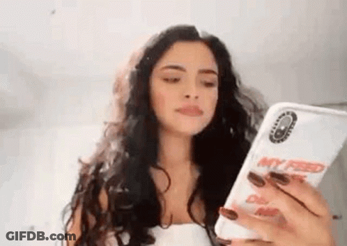 A Woman Is Holding A Cell Phone In Her Hand . GIF